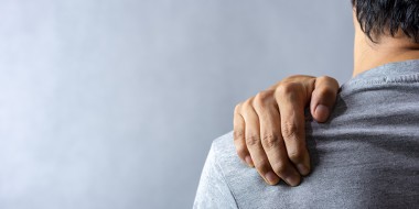 Persoon met hand op eigen schouders