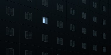 Flatgebouw in het donker met 1 verlicht raam