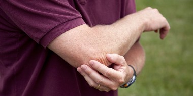 Man die zijn elleboog vasthoudt.