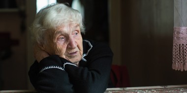 Vrouw op leeftijd zit aan tafel
