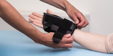 Twee handen die een handschoen aantrekken bij een derde hand.