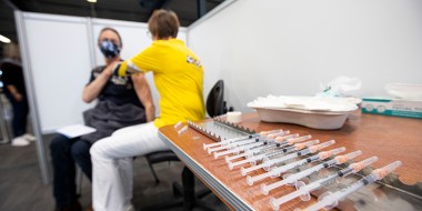 Persoon wordt gevaccineerd met op de voorgrond injectienaalden