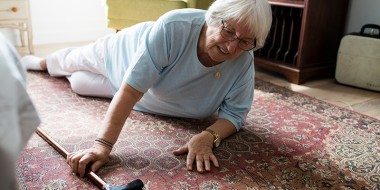 Oudere vrouw ligt op de grond in een huiskamer