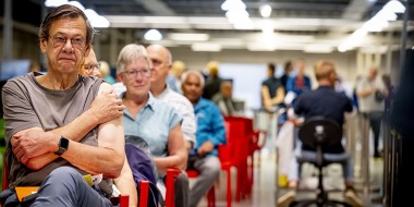 Rij van zittende mensen die zojuist gevaccineerd zijn